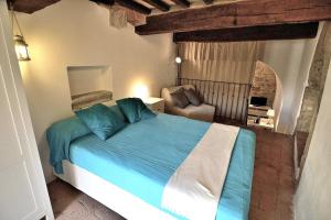 1 dormitorio con 1 cama azul y 1 silla en Authentic Cave House in the heart of the Village! en Massa Marittima