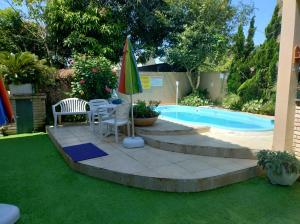 um quintal com piscina, guarda-sol e cadeiras em Casa da Oma em Penha