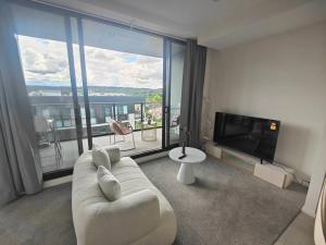 a living room with a couch and a large window at Brand New 2B1B Apt @ Inner North of Canberra in Canberra