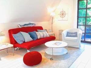 a living room with a red couch and a white chair at Nordseewölckchen 1 in Katingsiel
