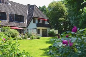 uma casa com um quintal com flores em frente em Nordseewölkchen 3 em Katingsiel