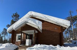 una baita di tronchi con neve sul tetto di Villa Länsitaalo a Kittilä