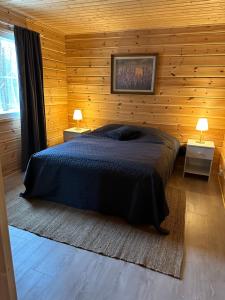 a bedroom with a bed in a wooden wall at Villa Länsitaalo in Kittilä