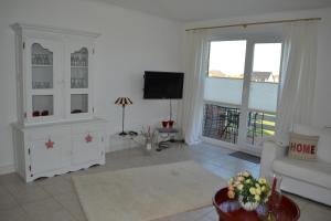 a white living room with a tv and a couch at Münstermann in Garding