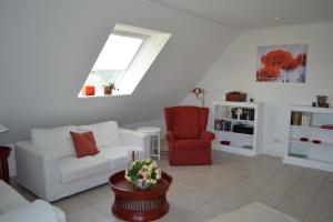 a living room with a white couch and a red chair at Münstermann in Garding