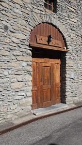 een stenen gebouw met een houten deur met een bord erop bij La casetta del cuore tra terme e montagna in Pré-Saint-Didier