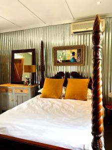 een slaapkamer met een bed met gele kussens en een spiegel bij Terebinte Bed & Breakfast in Durban