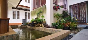 a house with a pond in front of a building at BBVC Hostel - CollegeStay in Ban Thurian