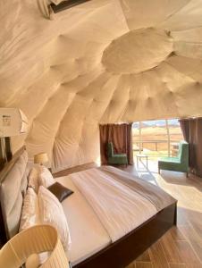 a large bed in a tent with two chairs at Rehana rum camp in Wadi Rum