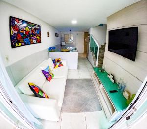 uma sala de estar com um sofá branco e uma televisão em casa de veraneio - casa 9 - condomínio azul mar - Porto de Galinhas em Porto de Galinhas