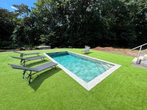 a swimming pool with two chairs and a bench in the grass at Appartement Bois Banane in Lamentin