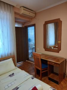 a bedroom with a desk and a bed and a mirror at Hotel Peja in Peje