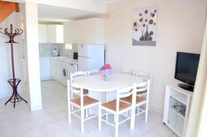 uma cozinha branca com uma mesa e cadeiras brancas em Gîte 5 avec piscine - plage 3kms em Clohars-Carnoët