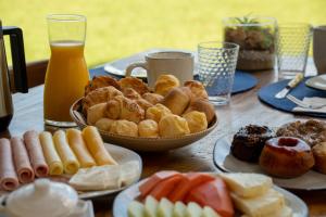 a table topped with plates of pastries and orange juice at Hotel Velas do Engenho in Ilhabela