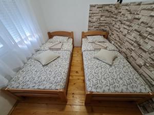 two beds in a room with a brick wall at Apartment Čolović in Raška