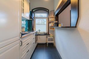 Una cocina con gabinetes blancos y un fregadero y una ventana. en Lütte Kajüte, en Tönning 12 fotos más