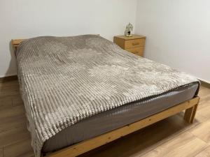 ein Bett mit einer grauen Decke darüber in der Unterkunft Charmant appartement Cosy in Reichstett