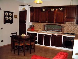 Una cocina con gabinetes de madera y una mesa con sillas. en Casa Papacqua, en Castellina Marittima