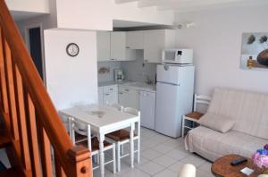 una pequeña cocina con mesa y nevera blanca en Gîte 3 avec piscine - plage 3kms, en Clohars-Carnoët