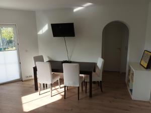 a dining room table with white chairs and a television on the wall at Idyllische Lage im Süden Erfurts in Erfurt