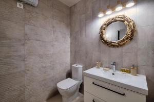 uma casa de banho com um WC, um lavatório e um espelho. em Varkiza Beach House em Vári