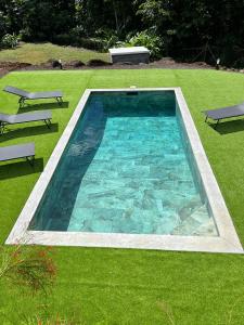 a swimming pool in the middle of a grass field at Chambre Paradise in Lamentin