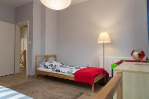 a bedroom with a bed with a red blanket and a lamp at VacationClub - Nadrzeczna VacationHome 1 in Ustroń