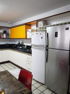 a kitchen with a stainless steel refrigerator and a red chair at Casa Aeroclube in João Pessoa