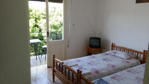 a bedroom with a bed and a television and a balcony at Marina's Rooms in Lipsoi