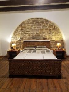 Cama grande en habitación con pared de piedra en Chante Ruisseau - Petit Havre de paix Breton, en Plouguenast Langast