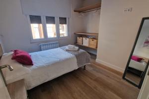 1 dormitorio con cama con almohadas rojas y espejo en Apartamento Aires de Tineo, en Oviedo