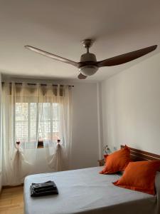 Un dormitorio con ventilador de techo y una cama con almohadas naranjas. en La Casita de Gio., en Tazacorte