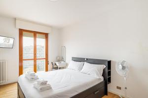 una camera da letto con un letto con lenzuola bianche e una finestra di Padova Station - Bright Apartment with Balcony! a Padova