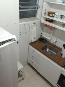 una pequeña cocina con fregadero y nevera. en AP Floripa, en Florianópolis