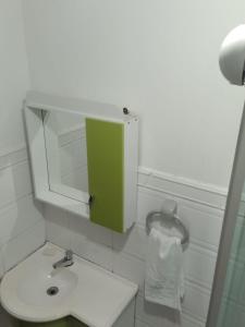 a white bathroom with a green cabinet above a sink at AP Floripa in Florianópolis