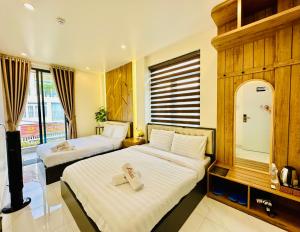 una camera d'albergo con due letti e uno specchio di Agape Hotel & Căn hộ Đà Lạt a Da Lat