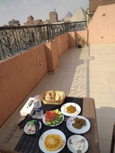 einen Tisch mit Tellern aus Essen auf einem Balkon in der Unterkunft Pyramids Road in Kairo