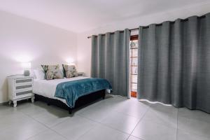 a bedroom with a bed and a window with curtains at Cornerstone Guesthouse in Cape Town