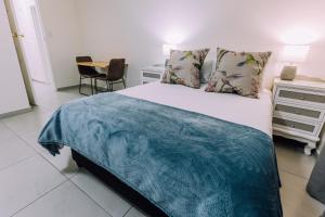 a bedroom with a bed with a blue blanket on it at Cornerstone Guesthouse in Cape Town