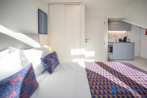 een slaapkamer met een wit bed met kussens en een keuken bij Porto Formosa Central Lofts in Porto