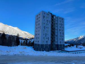 un edificio alto en la nieve junto a una montaña en Appartamento Biancaneve, en Passo del Tonale
