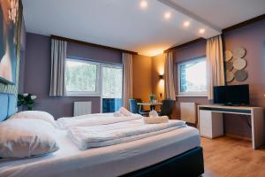 Un dormitorio con dos camas y un escritorio y dos ventanas. en The Art and Sporthotel, en Innsbruck