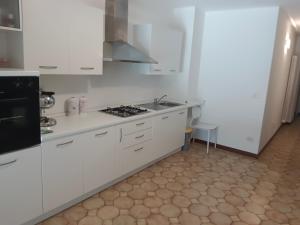 La cuisine est équipée de placards blancs et d'un four avec plaques de cuisson. dans l'établissement Terrace Home, à Saint-Vincent