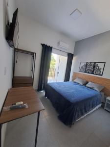 um quarto com uma cama azul e uma mesa em Residencial Dona Francisca em Florianópolis