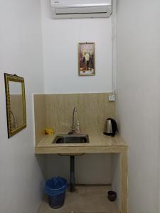 um balcão de cozinha com um lavatório e um espelho em Depulauserai Roomstays em Pekan