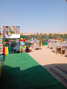 un patio con pavimento verde, tavoli e sedie di El Prince Guesthouse a Aswan