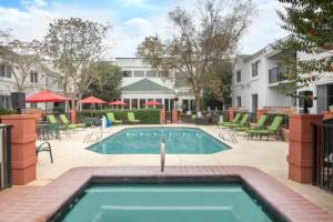 a swimming pool in a courtyard with chairs and a building at Wingate by Wyndham Valdosta/Moody AFB in Valdosta