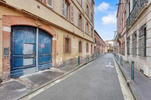 une rue vide avec une porte bleue sur un bâtiment dans l'établissement Le Cilaos - Superbe appt en centre ville, à Toulouse