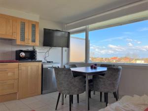 een keuken met een tafel en stoelen en een groot raam bij Bel Acacia in De Haan