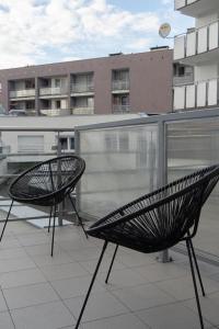 zwei schwarze Stühle auf einem Balkon mit einem Gebäude in der Unterkunft Apartament Wojskowa 1 / City Park in Posen